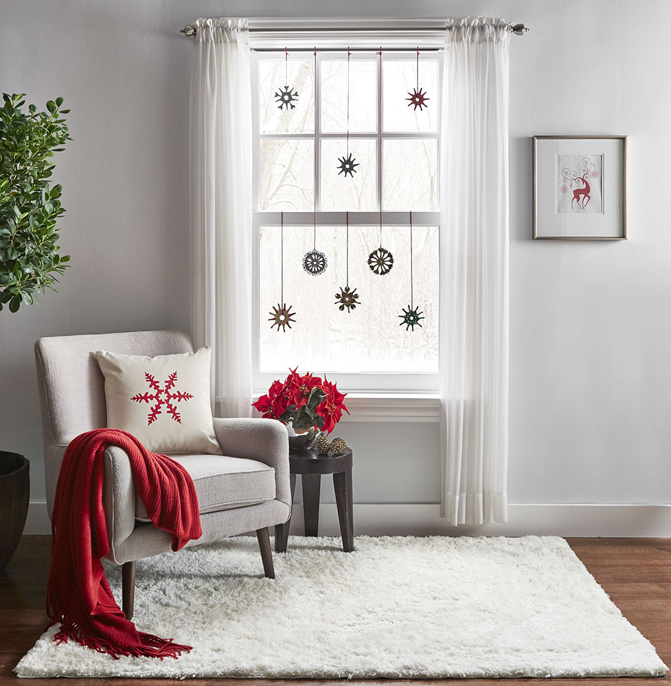 Snowflake ornaments made from keys hanging in front of a window.