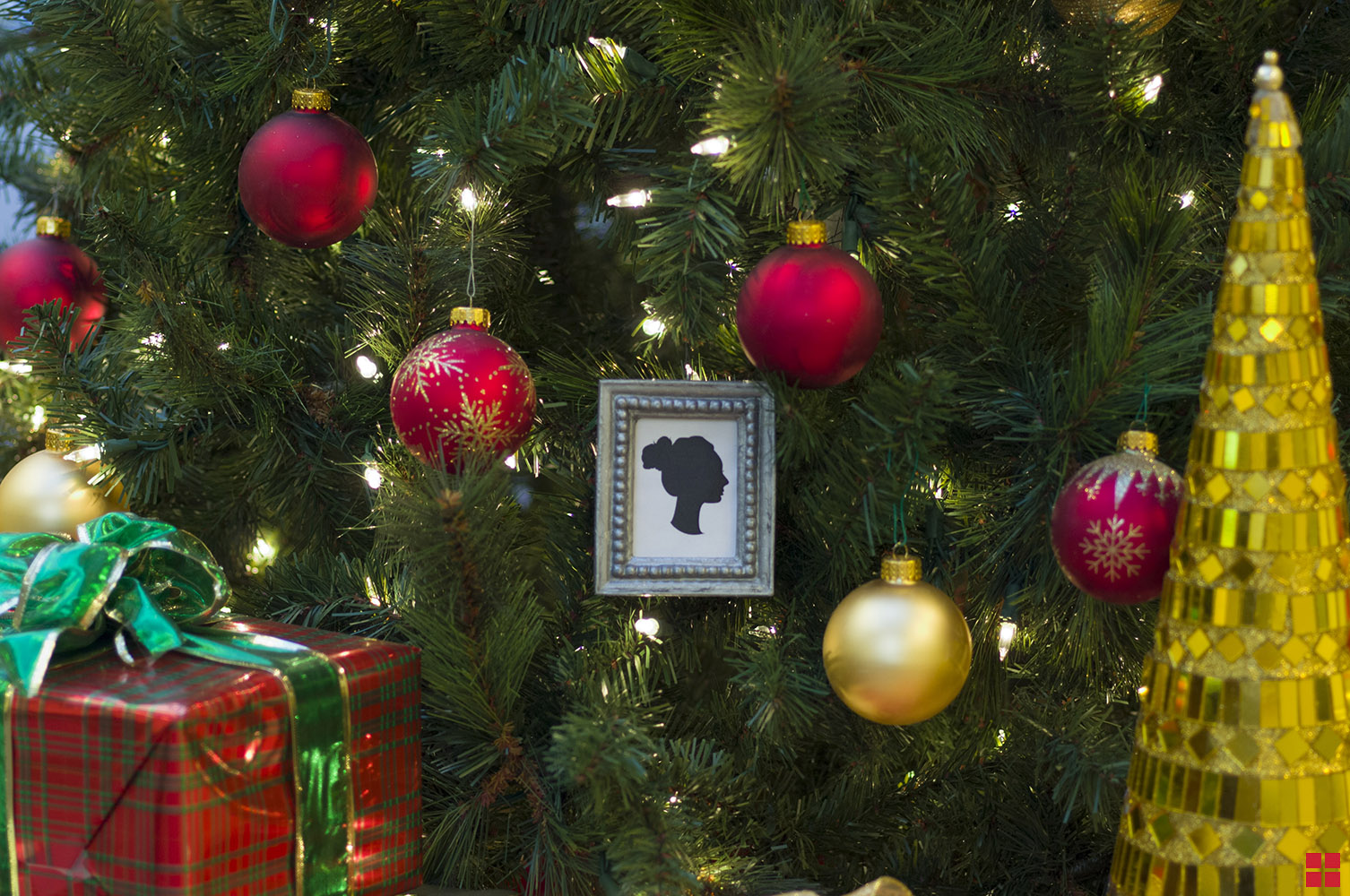 Spray painted picture frame ornament hanging on a Christmas tree.