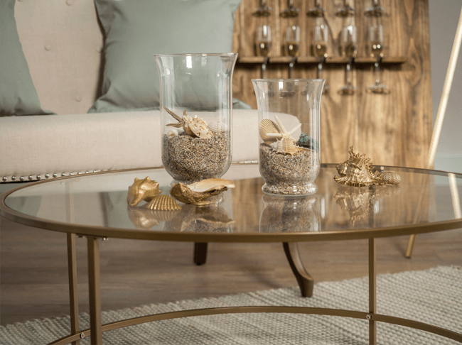 Gold painted seashells on a table next to vases filled with sand and shells.