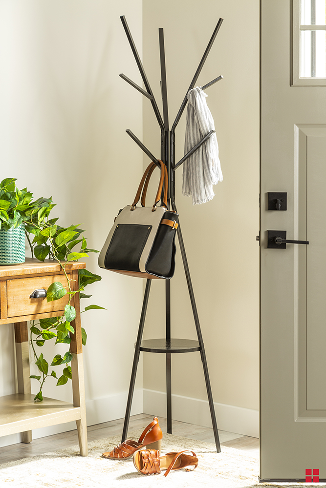 A black coat rack holding a purse and a white scarf. 