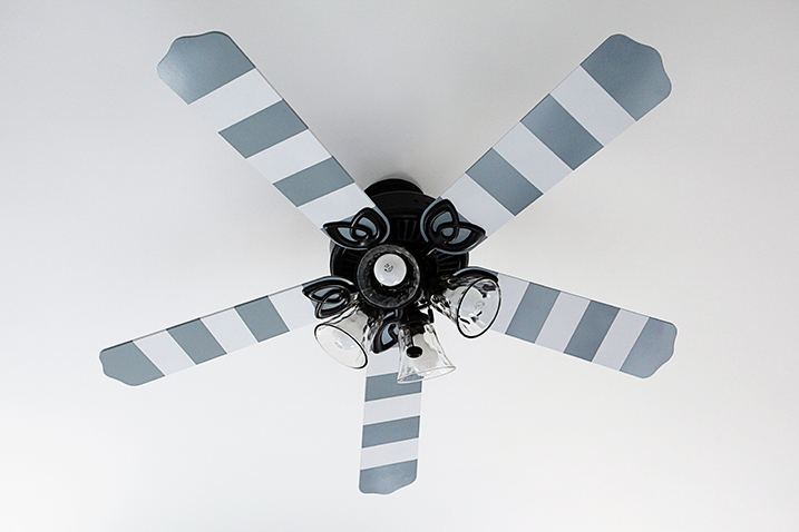 Ceiling fan with blades painted with white and blue stripes