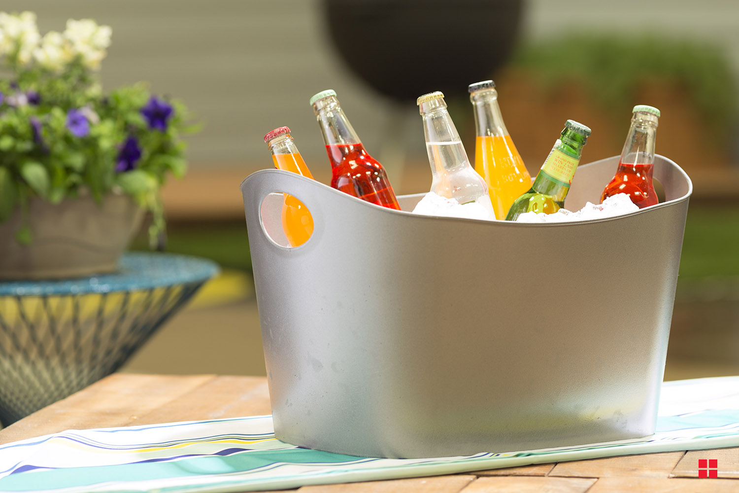 A silver cooler filled with ice and bottled beverages. 