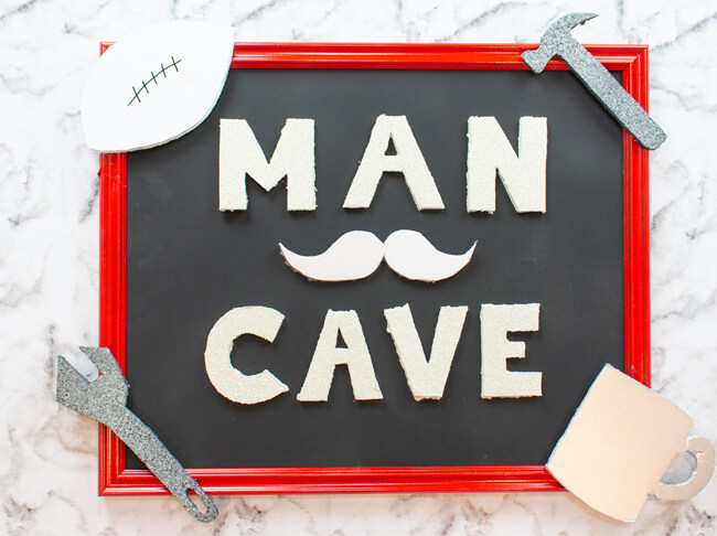 Man cave sign decorated with a mustache, tools, football and coffee cup.