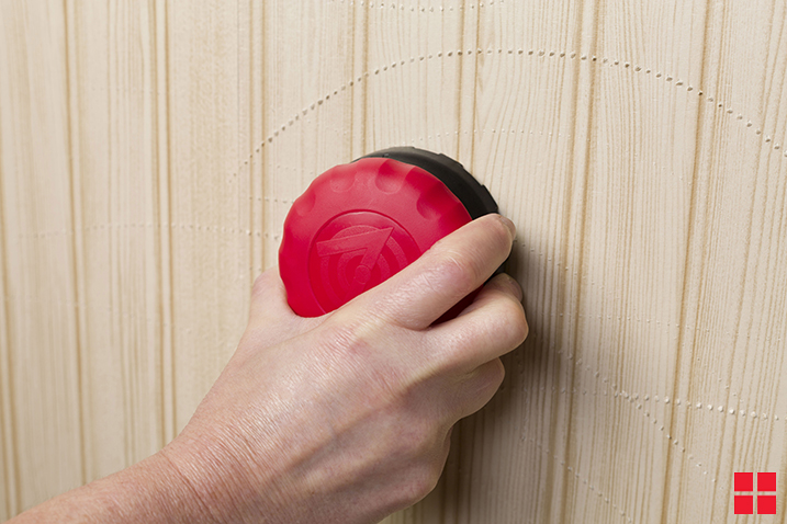 Person scoring wallpaper with Zinsser PaperTiger Scoring Tool.