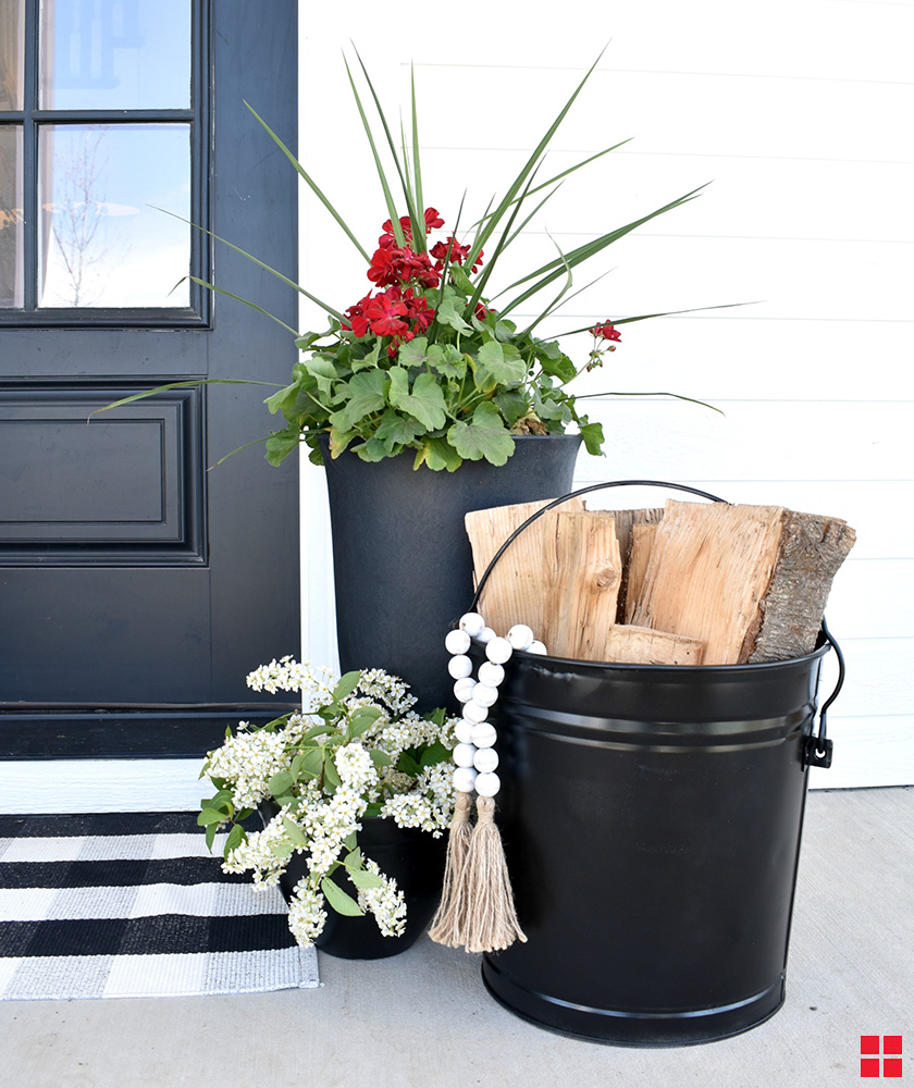 Black metal bucket and planter on a front porch.