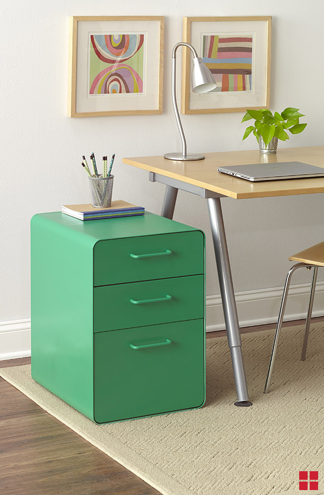 A green filing cabinet with three drawers next to a desk. 