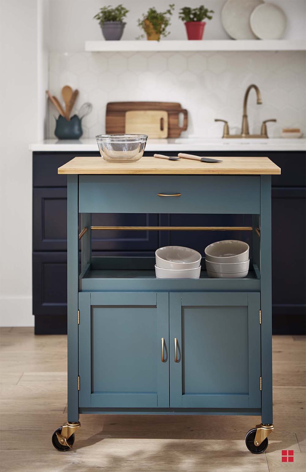A green kitchen island cart with a wooden counter and gold hardware. 