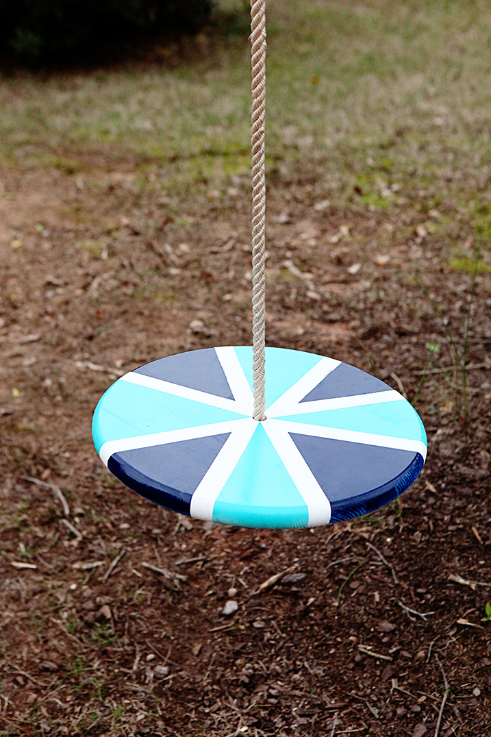 flat round wooden swing painted blue and white with a rope attached at the center