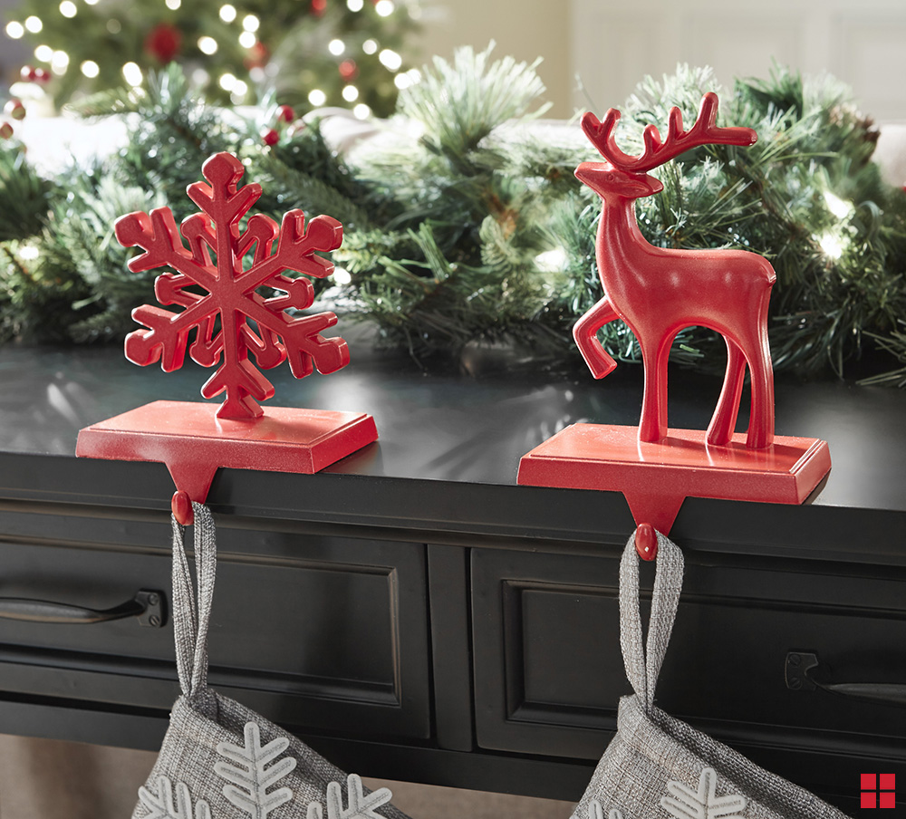 Red snowflake and reindeer stocking holders on a mantel. 
