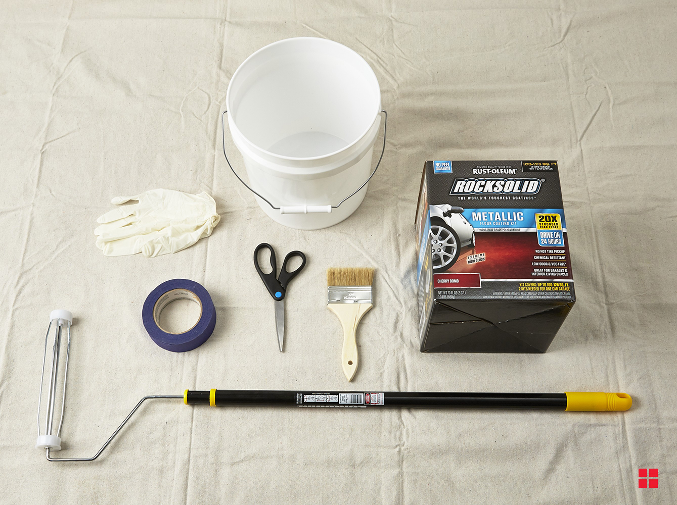 Drop cloth under a bucket, painting supplies and RockSolid Metallic Floor Coating kit.