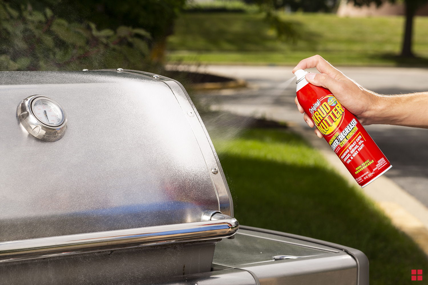 Spraying Krud Kutter Cleaner & Degreaser on the cover of a gas grill.