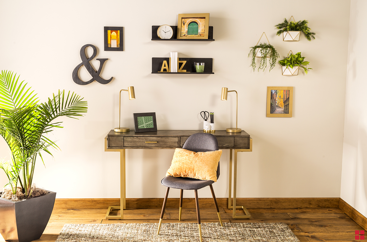 A home office with a desk, chair and potted palm tree and shelves, pictures and planters hanging from the wall. 