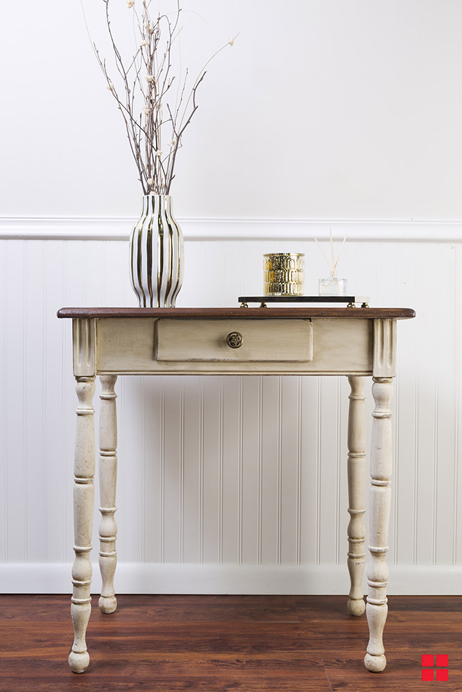 Entryway wood table with an antique white paint finish and a vase on top. 
