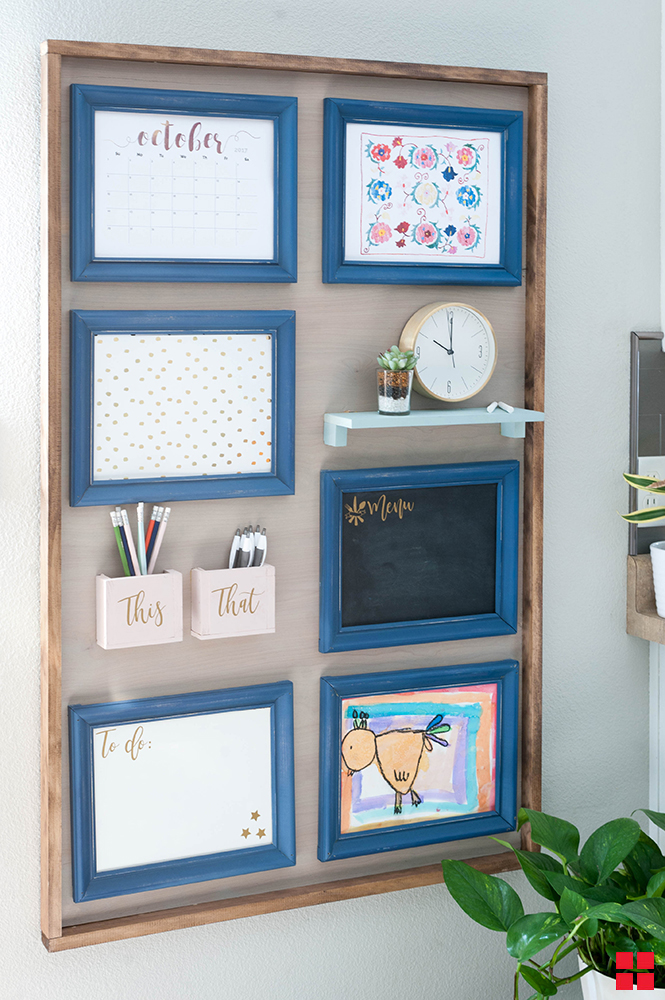 A wall featuring blue picture frames around artwork, a calendar, chalkboard and dry erase board.