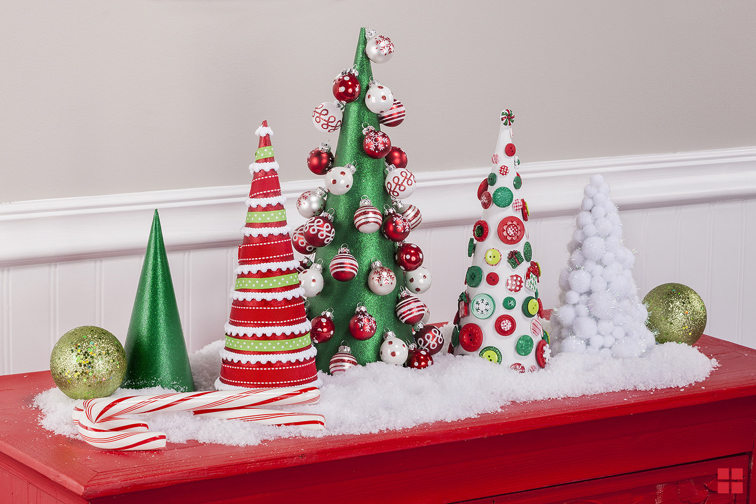Glittery Christmas trees decorated with buttons and ribbons displayed on a table.