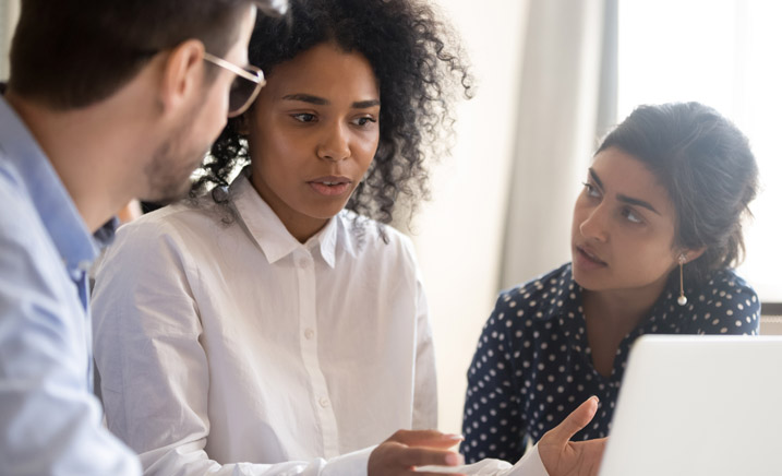Three interns talking by computer.