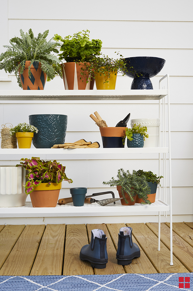 Potted plants and gardening tools on an outdoor shelving unit.