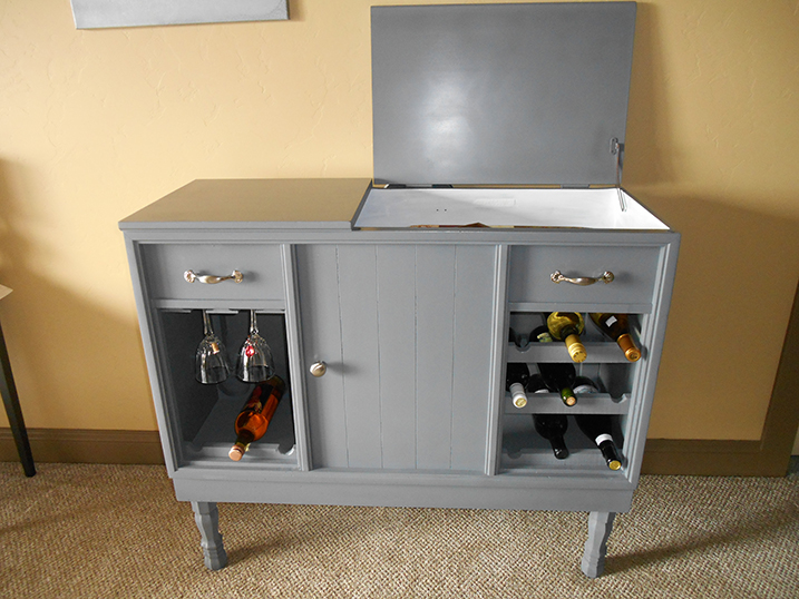 Painted gray cabinet with a built-in wine rack and glass holder.