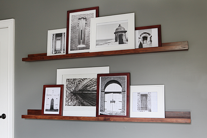 Photo frames on top of dark stained wooden shelves attached to a wall