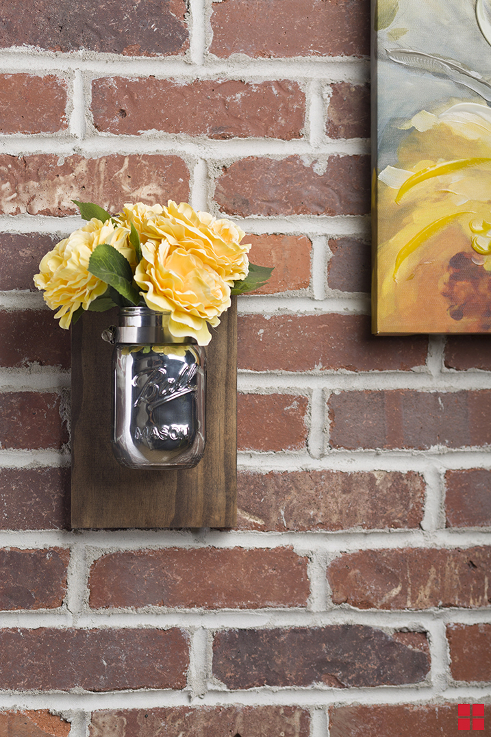 Mason jar vase with a mirror glass finish mounted to a wooden board to make a wall sconce.