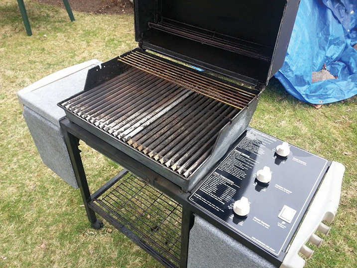 A gas grill with the top open and clean side burners.