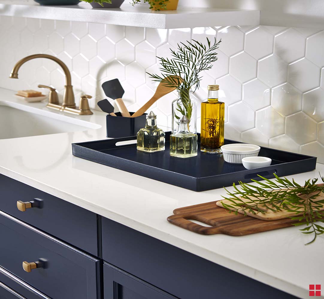 A navy blue serving tray holding bottles of olive oil and two small white bowls. 