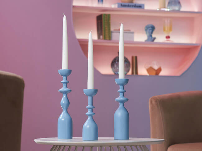 Three light blue candlesticks with white candles in them. 