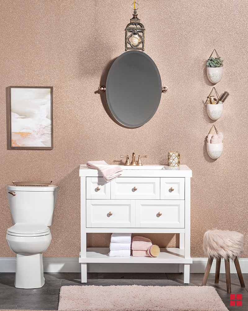 Rose gold glitter paint on a wall behind a toilet and sink.