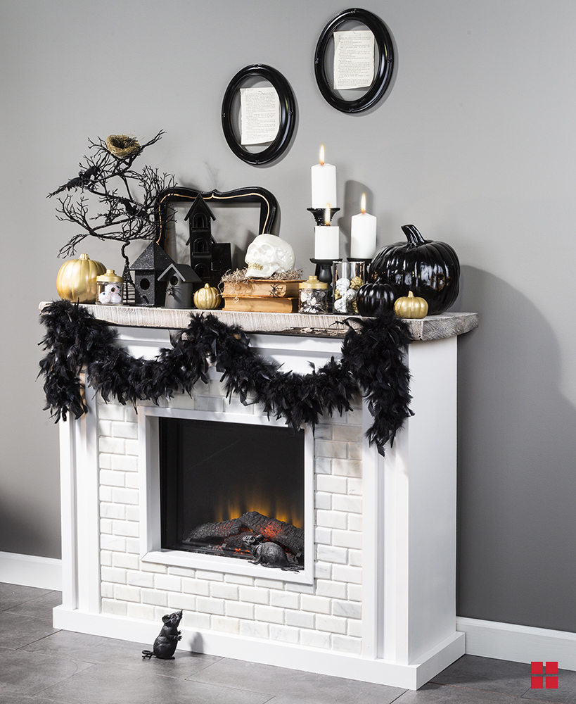 A white brick fireplace with black garland, decorative pumpkins, candles and a skull on the mantel.