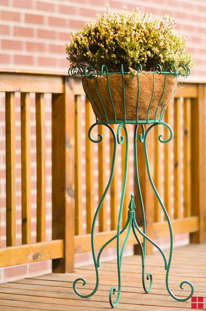 Green metal plant stand on a wooden deck.
