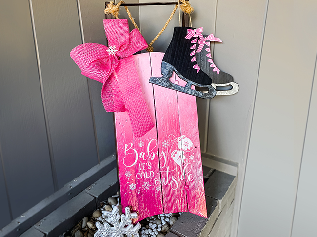 A vintage wooden sled painted with a pink ombre effect. 