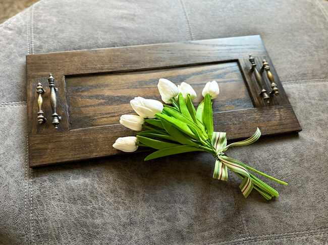 A bouquet of flowers over a wooden ottoman tray.