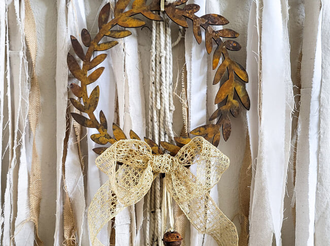 A rusty looking brown wreath with an off-white bow.