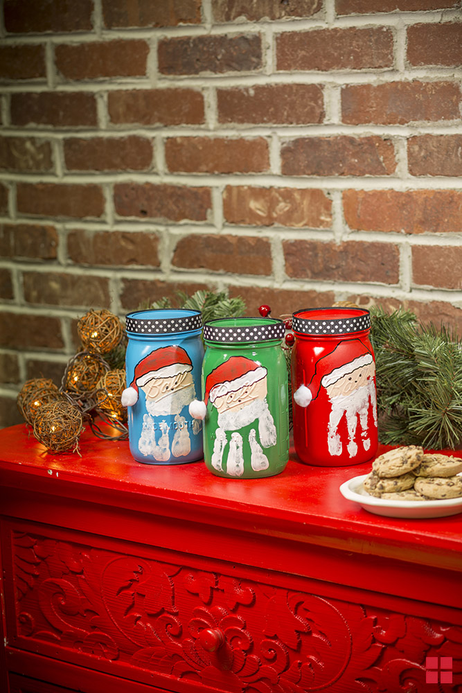 Three Mason jars each painted with a handprint Santa.