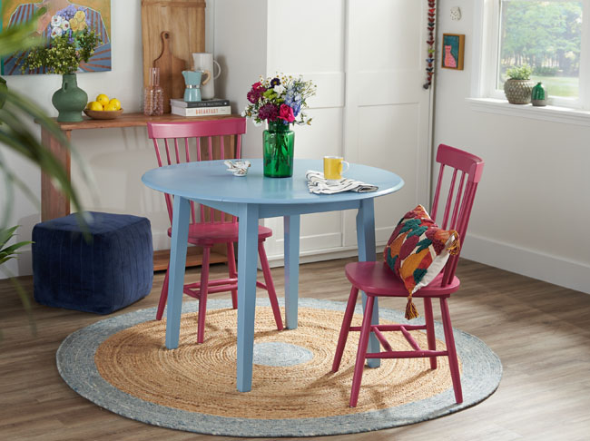 A light blue kitchen table with two dark pink chairs.