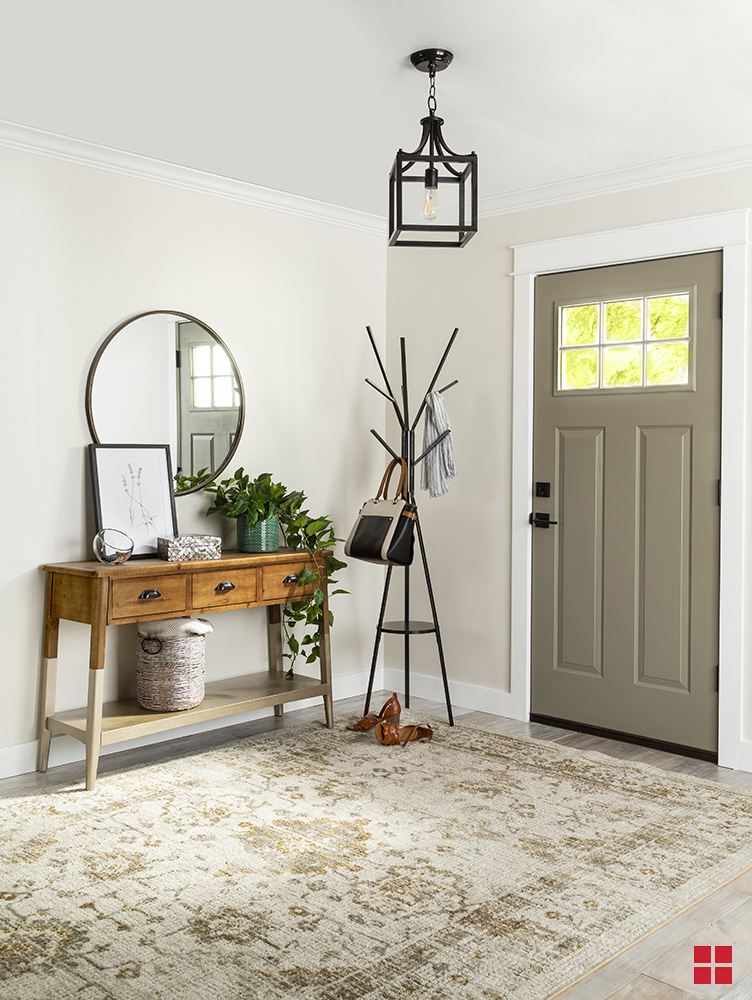 Entryway of a home with a light fixture, coat rack and mirror over a table with a potted plant and framed picture sitting on top.