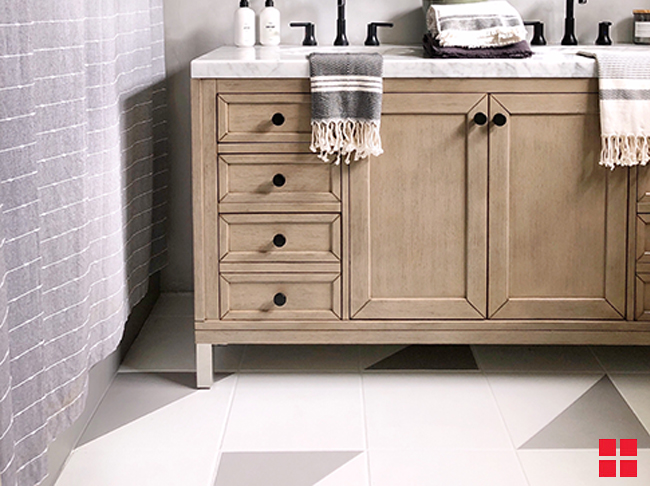 Wood vanity on an off-white and gray painted bathroom tile floor. 