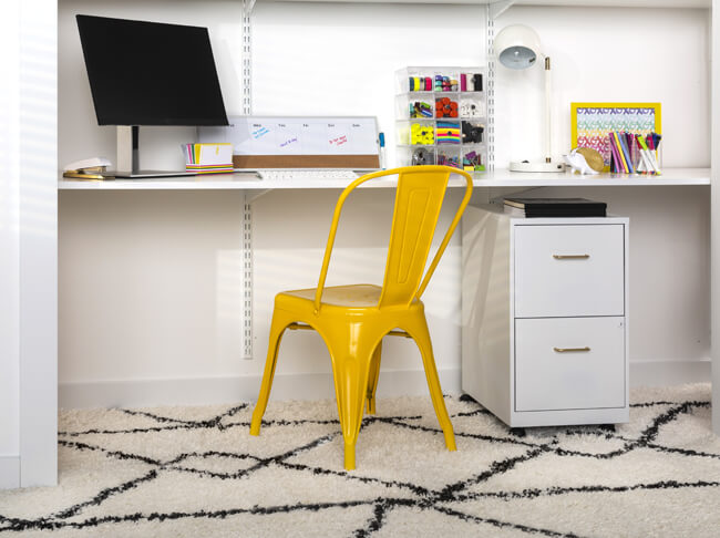 A home office space with a bright yellow metal chair.