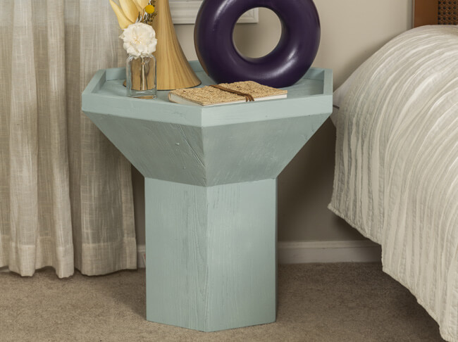 Light blue wood night stand next to a bed. 